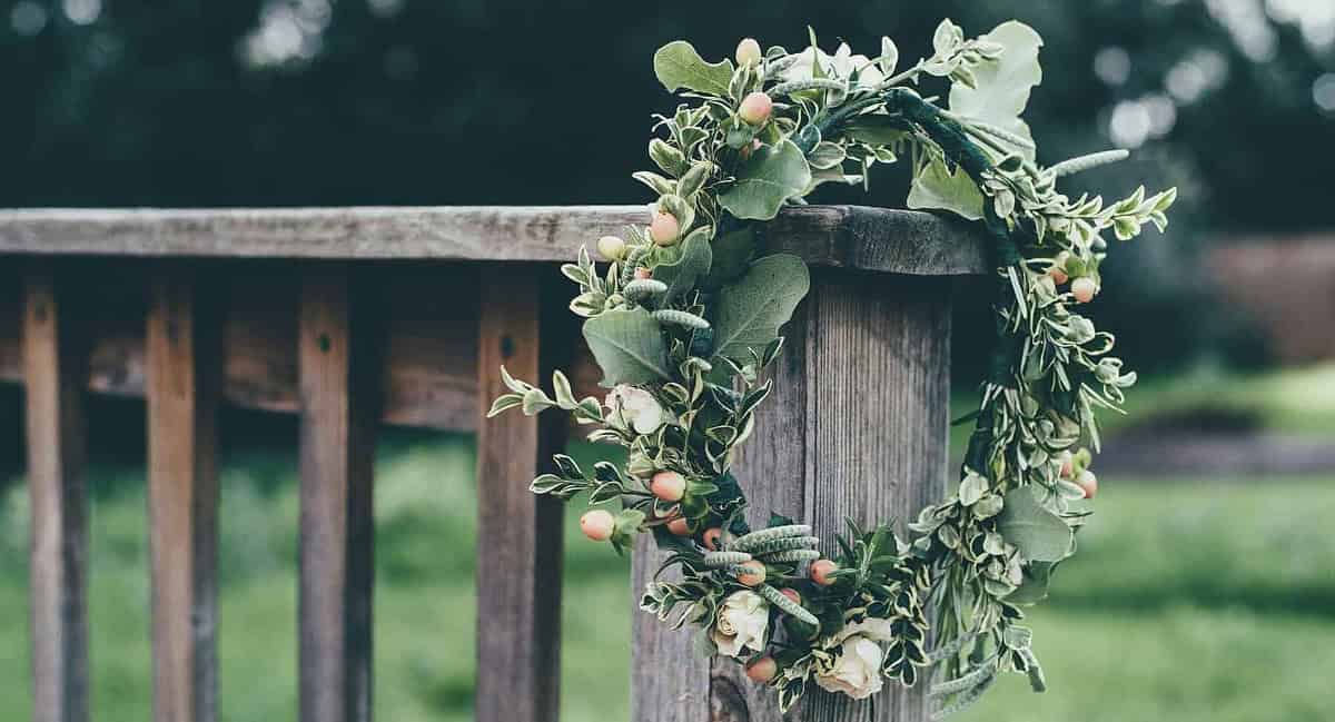 A wreath of flowers hanging on the side of a wooden fence.