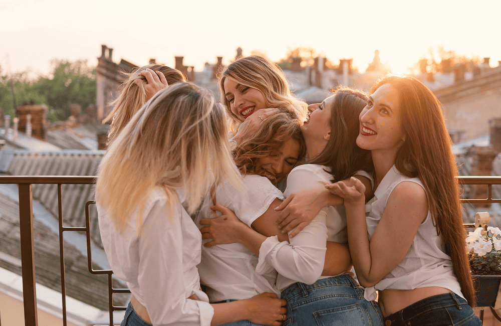 A group of women hugging on top of a building.