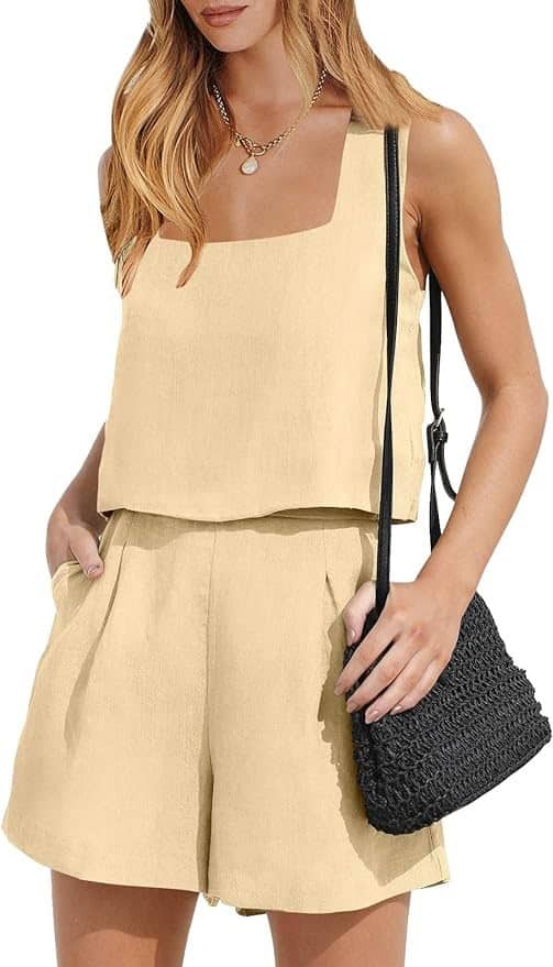 A woman wearing a beige outfit holding onto a black purse