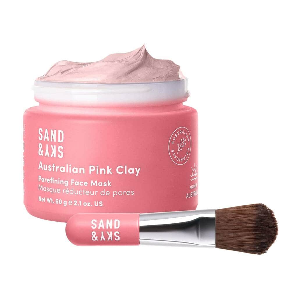 A pink face mask and brush on top of a white table.