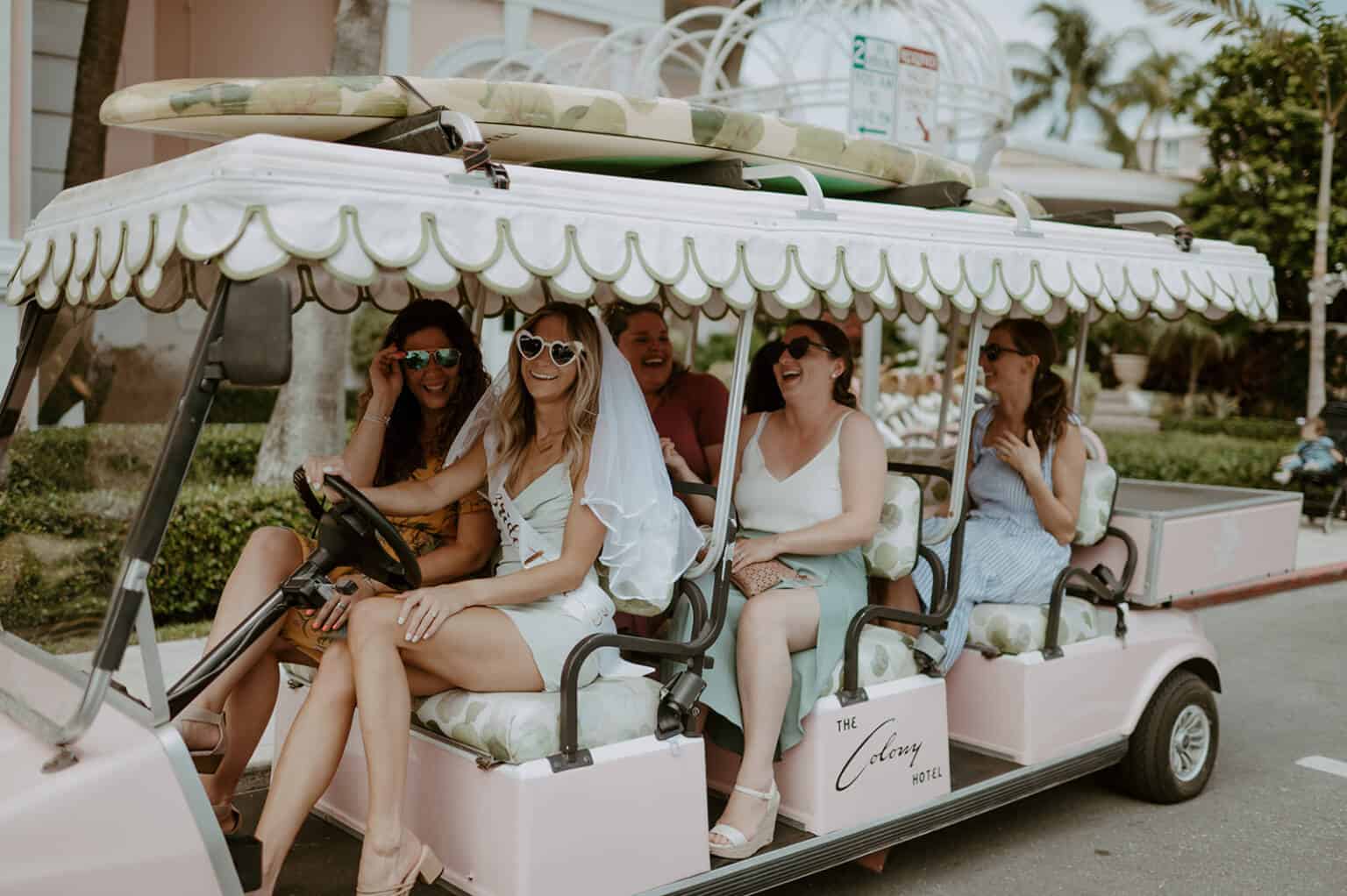 A group of people sitting on top of a pink bus.