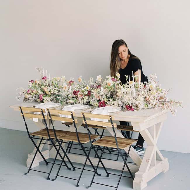 A Woman Sitting At The Table With Flowers On It