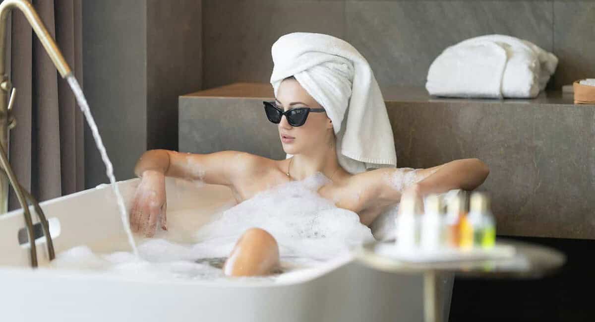 A woman in white towel sitting in a bath tub.