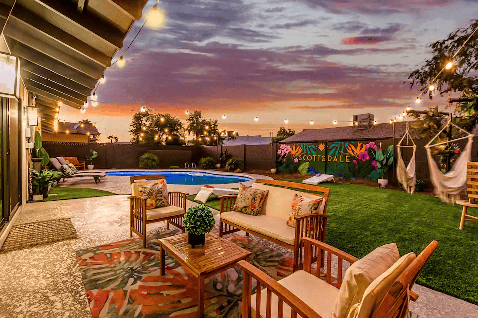 A patio with furniture and a pool in the background.