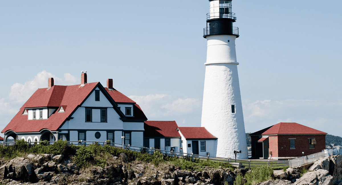 A lighthouse with a red roof and white building
