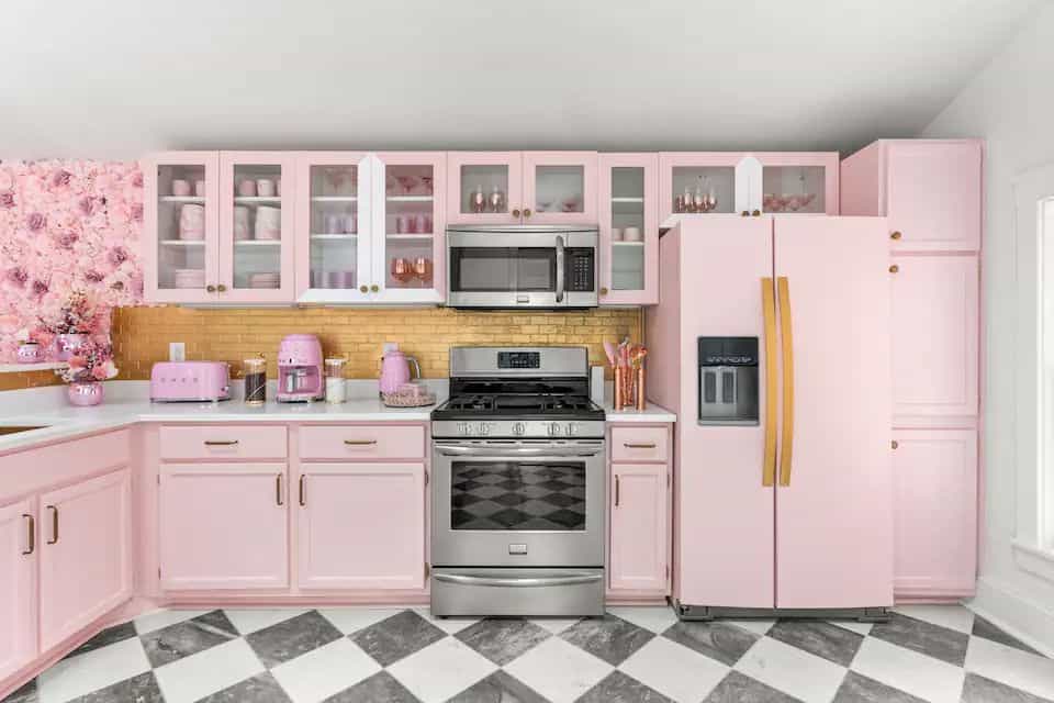 A kitchen with pink cabinets and black checkered floor.