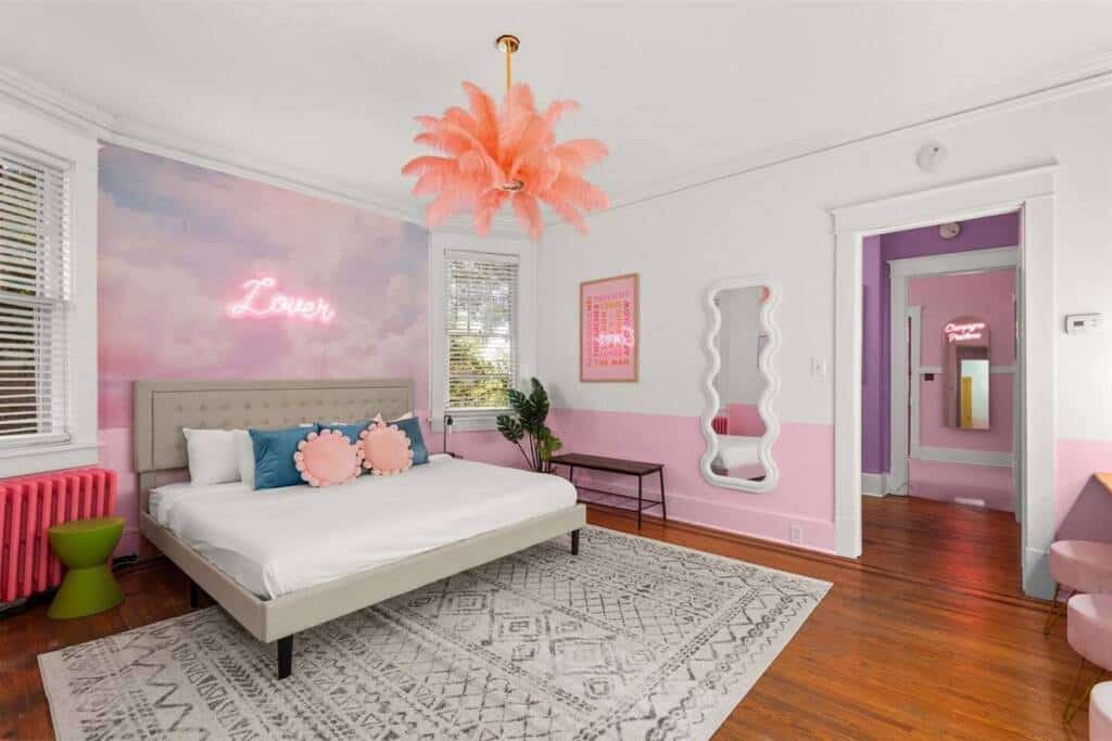 A bedroom with a bed, rug and pink wall.