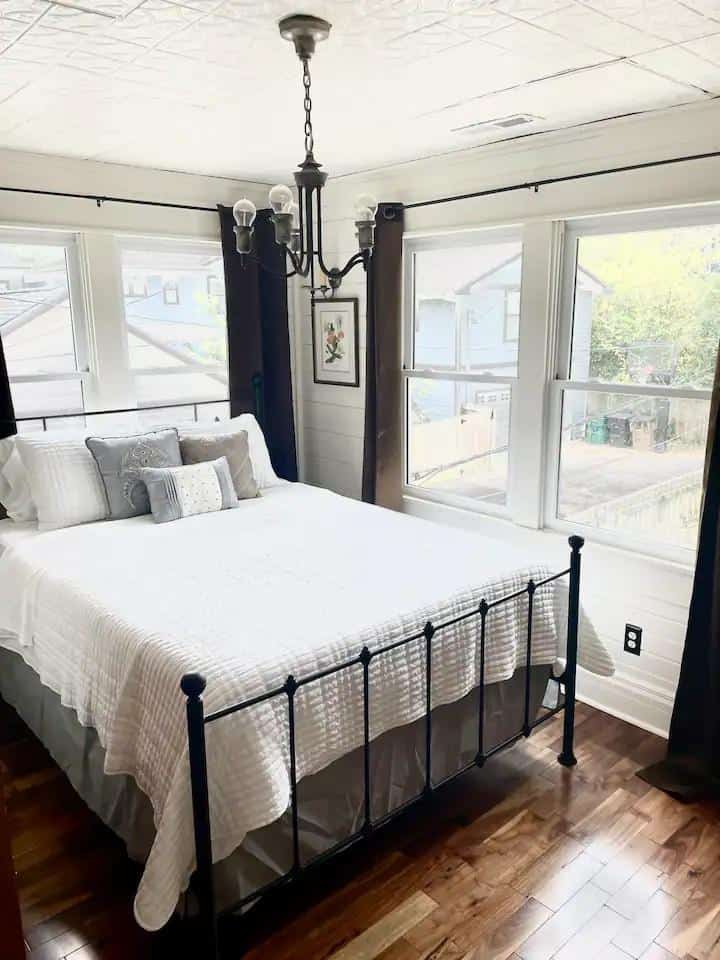 A bed room with a black metal frame and white sheets