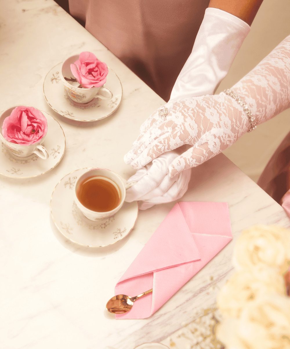 A person in white gloves holding a cup of tea.