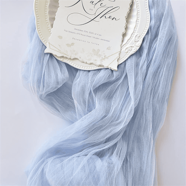 A plate with a wedding invitation and blue scarf.