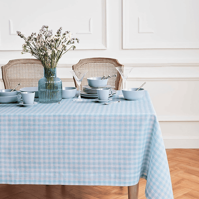 A table with blue checkered tablecloth and white dishes.